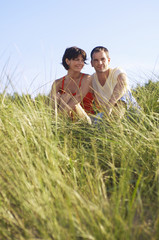 Young romantic couple sitting in tall grass at beach