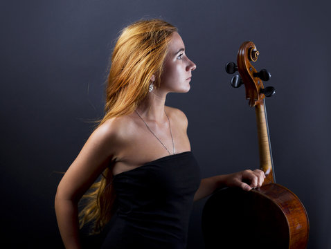 Beautiful girl with a cello in the dark. Violonchello. Girl with long straight hair