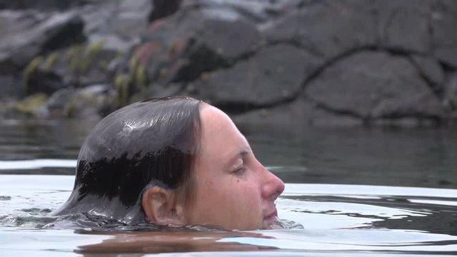 Slow motion young woman in bikini moving up form underwater to surface for air