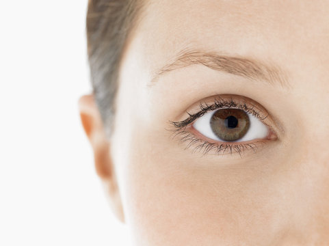 Closeup portrait of an eye of a young woman against white background