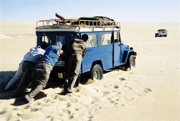 Men pushing jeep in desert © MDBPIXS
