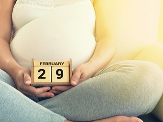 Baby's due date on leap day on a calendar with pregnant woman background. Maternity concept. Expecting an upcoming baby. Due date countdown.