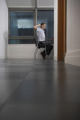 Full length side view of tired businessman stretching in office