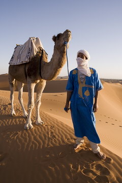 Berber man standing with his camel, Erg Chebbi, Sahara Desert, Merzouga, Morocco