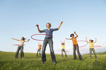 Fotobehang Full length of happy female friends playing with hula hoop against sky in park © moodboard