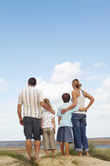 Rear view of a family standing on sand and looking at view on beach