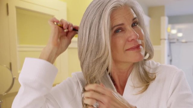 Closeup portrait of a mid aged woman combing her hair