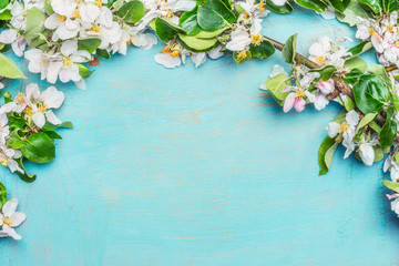 White Spring blossom on blue turquoise wooden background, top view, border. Springtime concept