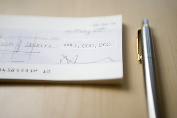 Cheque for one million dollars lying next to pen on table close-up