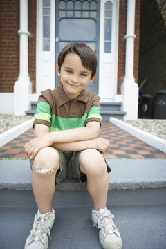 Portrait of happy little boy sitting on front steps of house