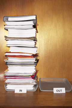 Inbox With Stack Of Paperwork Empty Outbox On Desk