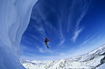 Low angle view of man jumping from mountain ledge against sky