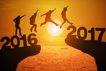 Silhouette group of young mans jumping between 2016 and 2017 years with beautiful sunset at the sea.