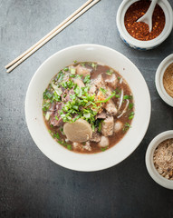 Asian style beef noodles soup with seasoning on dark stone background