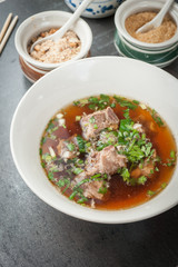 Asian style pork bone soup with seasoning on dark stone background