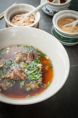 Asian style pork bone soup with seasoning on dark stone background