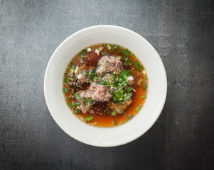 Asian style pork bone soup with seasoning on dark stone background