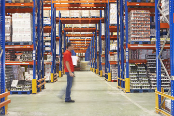 Side view of a blurred man walking through warehouse