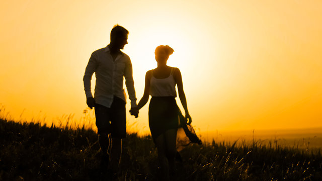 loving couple - brave young man and beautiful girl at sunset silhouette,