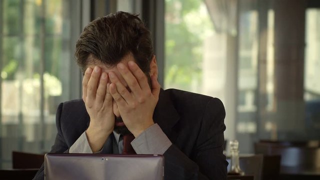 worried and depressed businessman sitting alone in a cafeteria