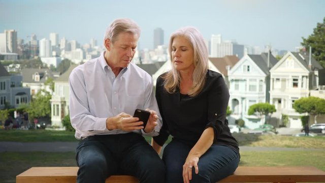 Mature caucasian male looking at cellphone with female friend in San Francisco