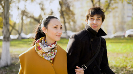 Couple in a wonderful mood to walks in the autumn city. As long  the baby is sleeping in his pram parents talk  each other.