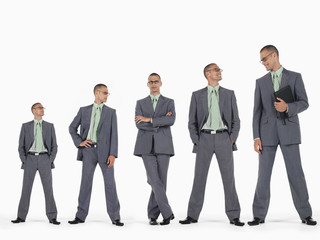 Row of businessmen in ascending order of height against white background
