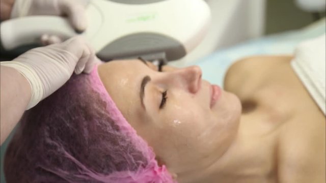 Young woman doing cosmetology laser therapy