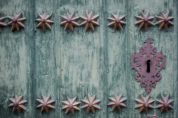 Keyhole in an old paneled wooden door; rusty and weathered
