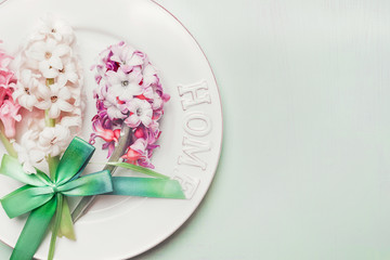 Festive table setting with spring flowers , plate and ribbon on light pastel wooden background, top view, copy space.