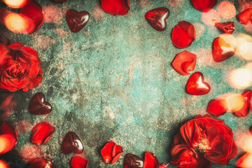 Valentines day background with red roses , petals , glass heart and bokeh lighting, top view, frame