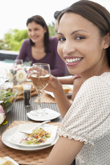 Portrait of happy young woman holding wineglass at dinner party