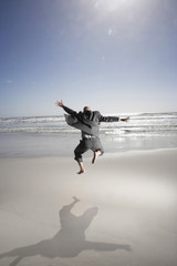 Fototapeta na wymiar Rear view of middle aged businessman jumping on beach