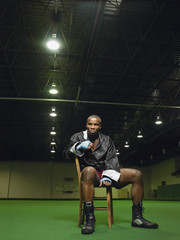 Full length portrait of an African American boxer sitting on chair