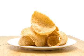 Pile of crunchy prawn cracker in a white plate on a wooden board