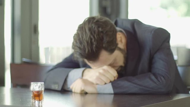 depressed businessman sitting in a cafè with a glass of alcohol