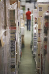 Warehouse full of cellophane wrapped goods with blurred man in the background