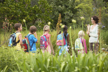 Young teacher with children on nature field trip - Powered by Adobe