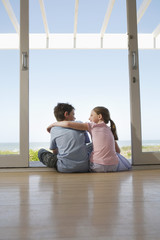 Rear view of young girl and boy sitting in doorway looking at each other