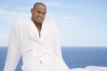 Portrait of African American man in bathrobe with ocean in background