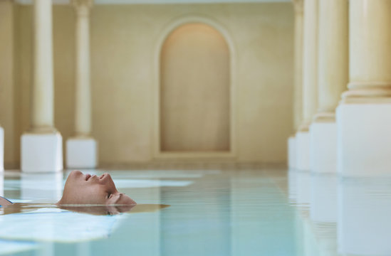 Young Woman Lying On Her Back Floating In Swimming Pool