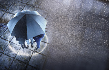 Elevated view of three businesspeople sheltering under one umbrella