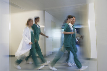 Side view of blurred physicians rushing through hospital corridor