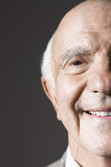 Extreme closeup of a smiling senior man against gray background