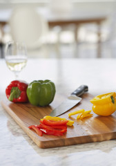 Peppers and knife on chopping board in kitchen