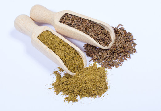Ground cumin in a spoon and whole cumin.