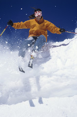 Low angle view of a skier through snow against clear blue sky