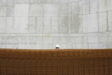 Side view of a man using cellphone behind stack of rebar at building site