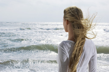 Rear view of a young blond woman looking at the ocean