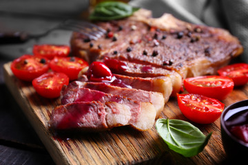 Grilled steak with tomatoes and basil on cutting board, closeup